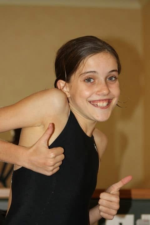 Olivia as a teenage swimmer giving two thumbs up